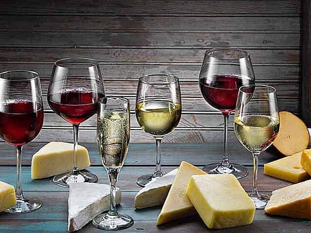 Red and White Wines and cheese on brown and teal wood