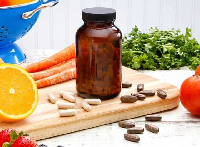 multivitamins, fruits and vegetables on cutting board