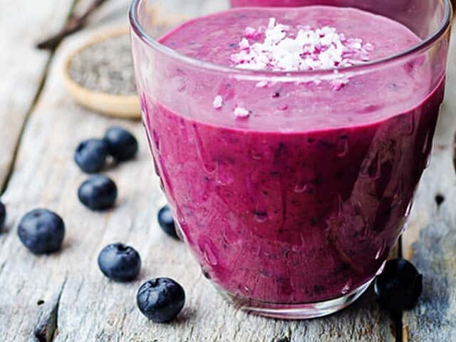 Blueberry smoothie and blueberries on table