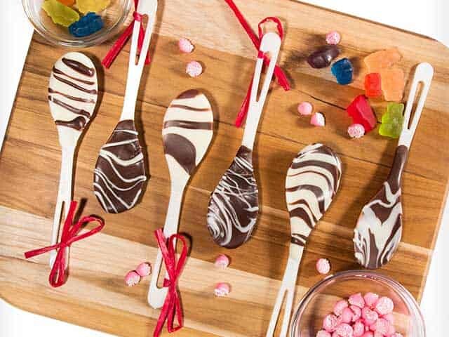 Spoons covered in chocolate with candies on the side