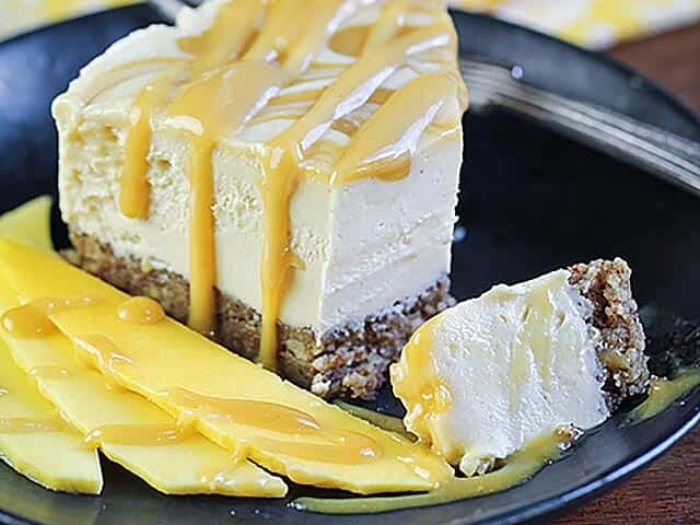 vegan mango cheesecake on plate with slices of mango