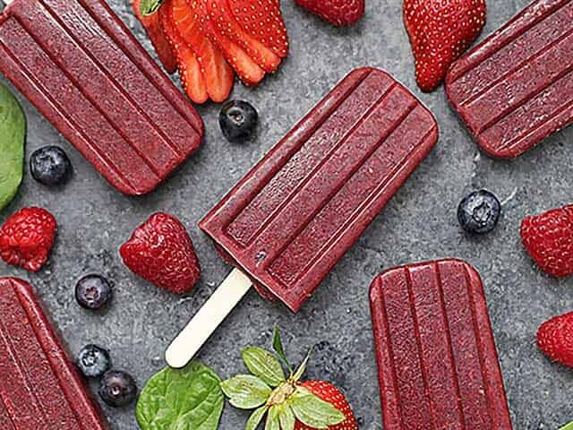 Superfood Very Berry Popsicles displayed with fresh fruit