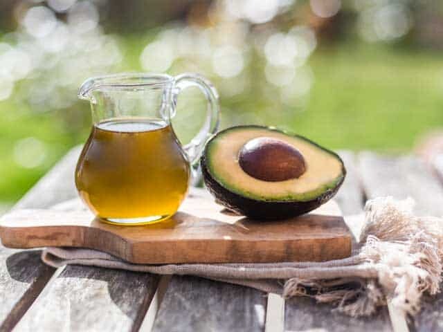 Paleo Healthy Fats - Avocado Oil shown with half an avocado on cutting board