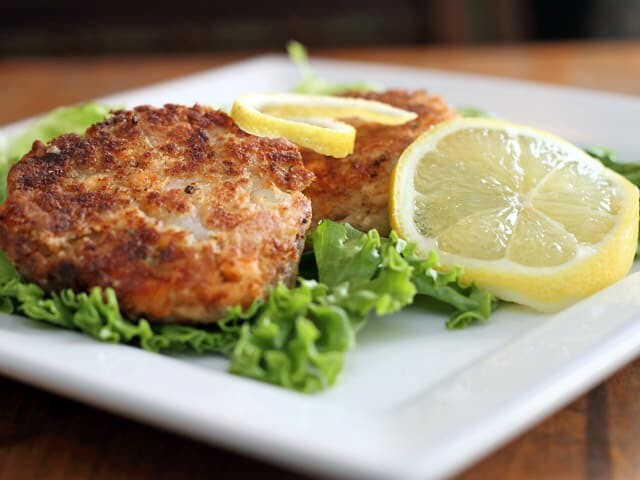 Plate of salmon cakes with green lettuce and lemon slices