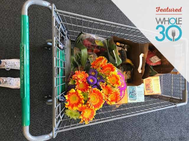 Sprouts grocery cart with Whole30 cookbook and flowers