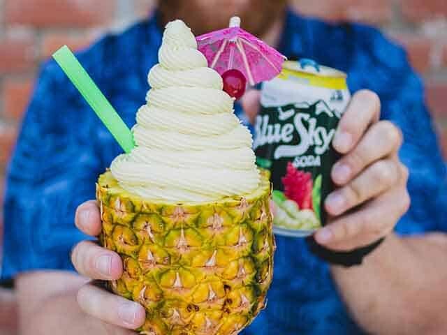 Someone holding a Blue Sky Soda and a fresh pineapple ice cream float