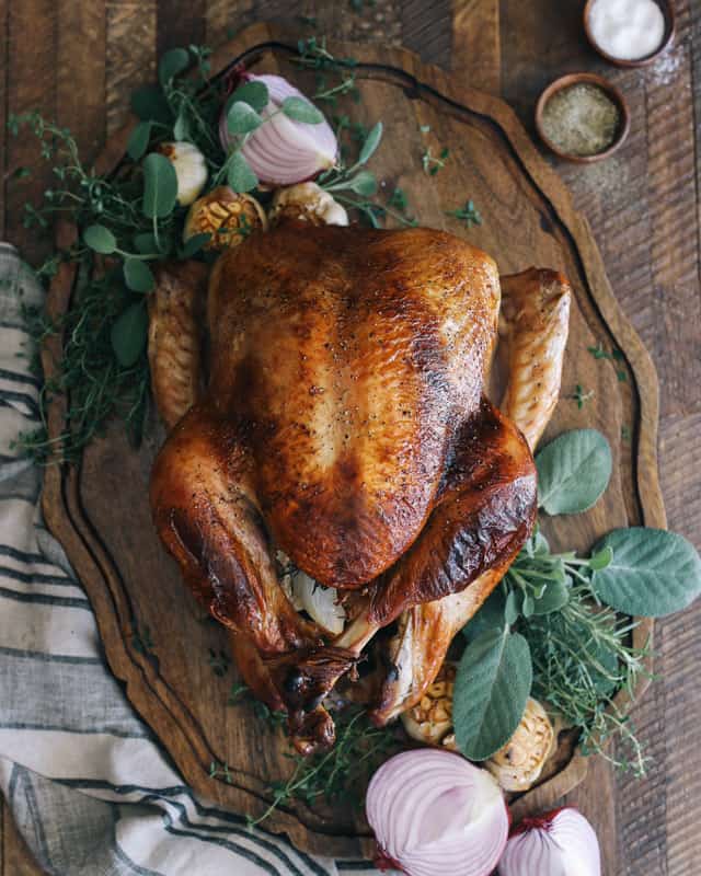 Roasted turkey on a platter with onion, rosemary and sage