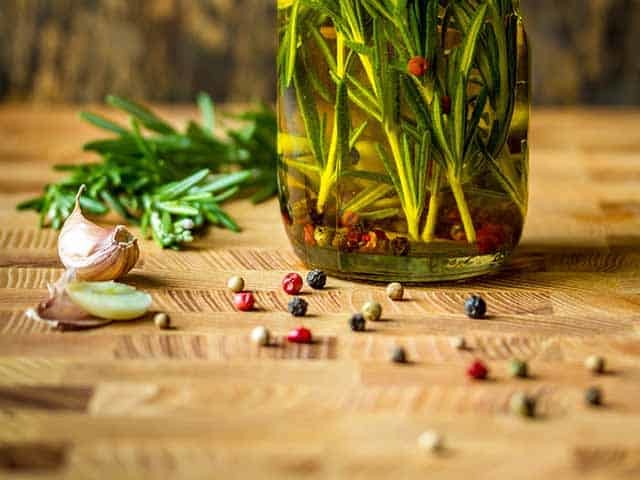 Olive oil bottle filled with rosemary, garlic and pepper to make the perfect brine