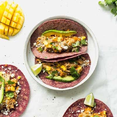 Enchilada Tacos on a plate with mango and lime