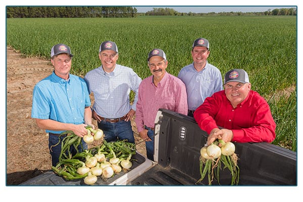 Shuman Farms Farmers holding onions.