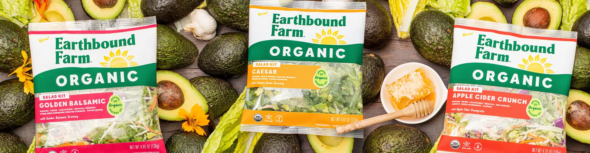 Earthbound Farms salad kits surrounded by avocados