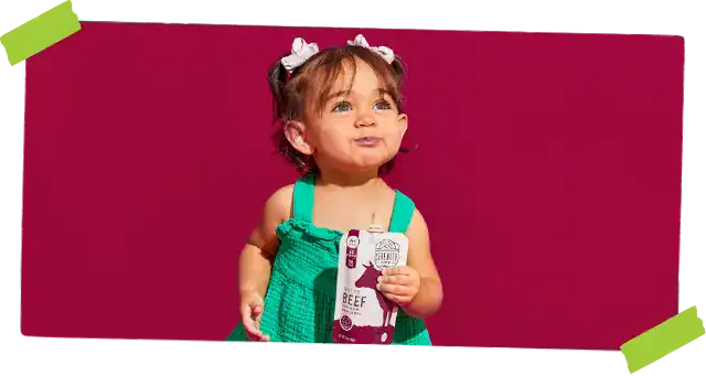 little girl holding a baby food pouch